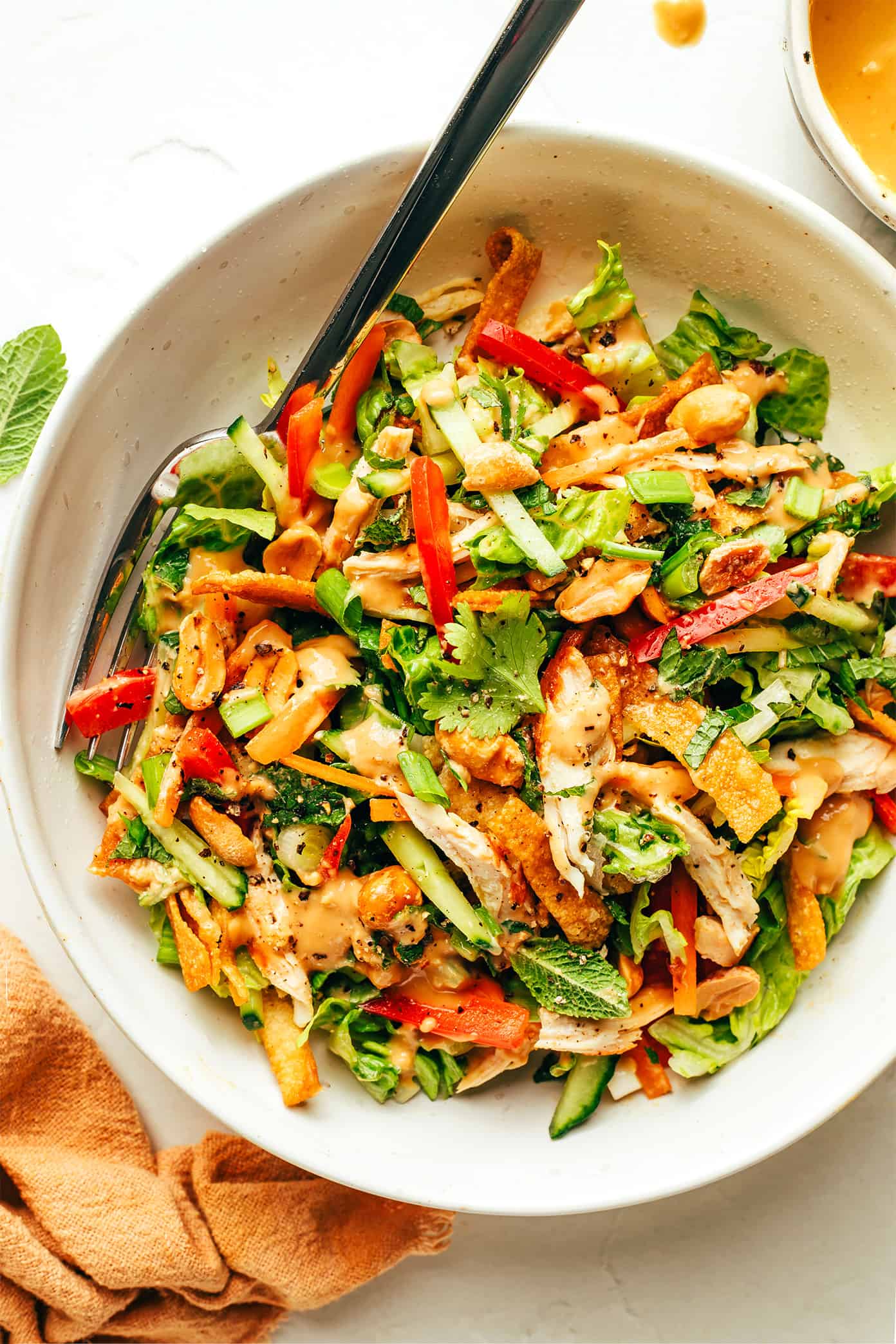 Thai Crunch Salad drizzled with peanut dressing in bowl with fork