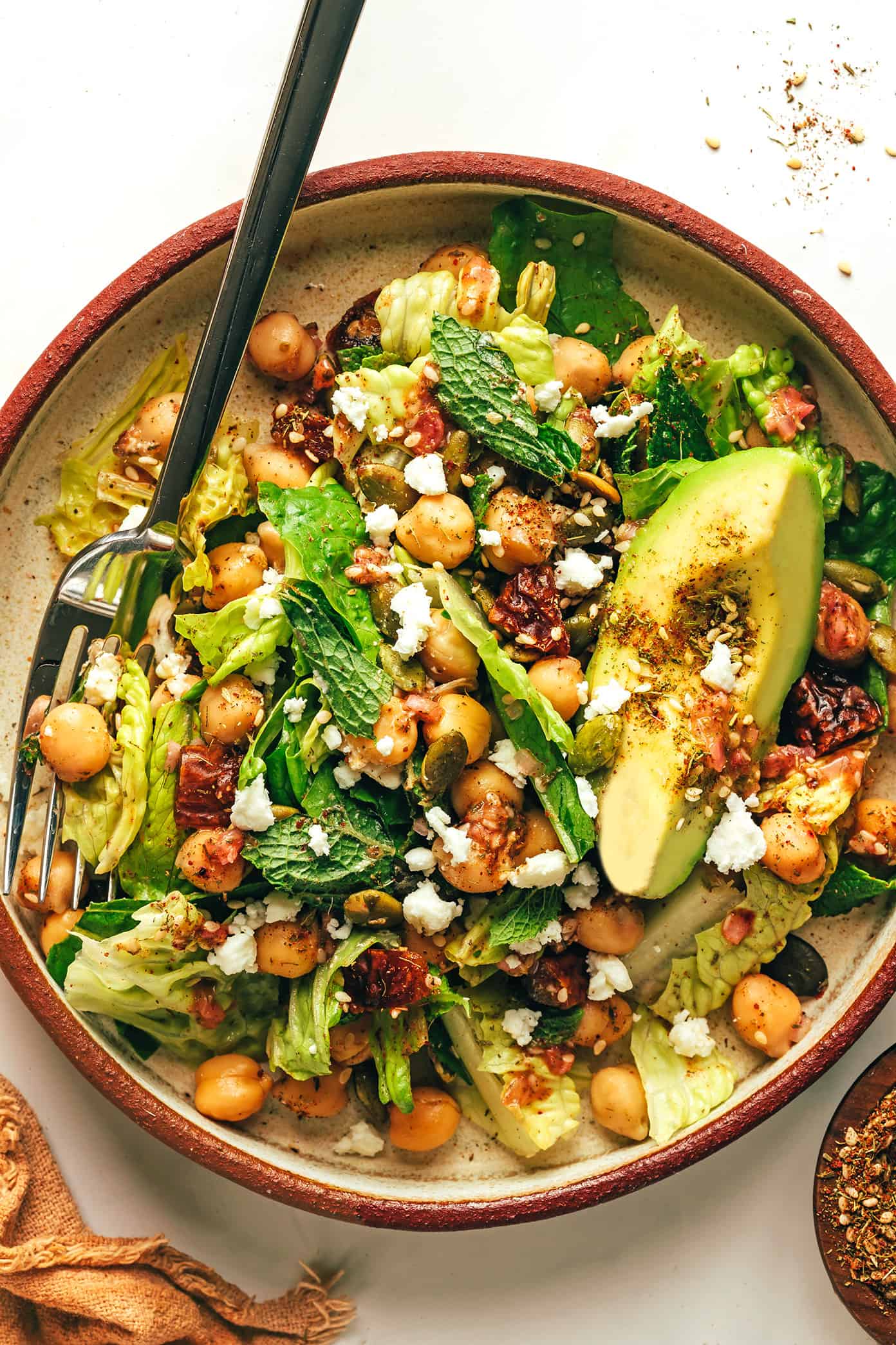 Chickpea avocado and avocado green salad with za'atar vinaigrette in serving bowl with fork